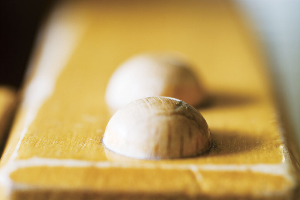 Primo piano di due protuberanze semicircolari in legno su una superficie gialla e liscia.
