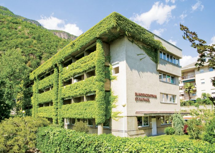 Ein Gebäude mit grüner Fassadenbegrünung und der Beschriftung Blindenzentrum St. Raphael im Vordergrund.